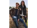 Bărbat și femeie în cămașă de flanel și jachete pe un balot de fân.