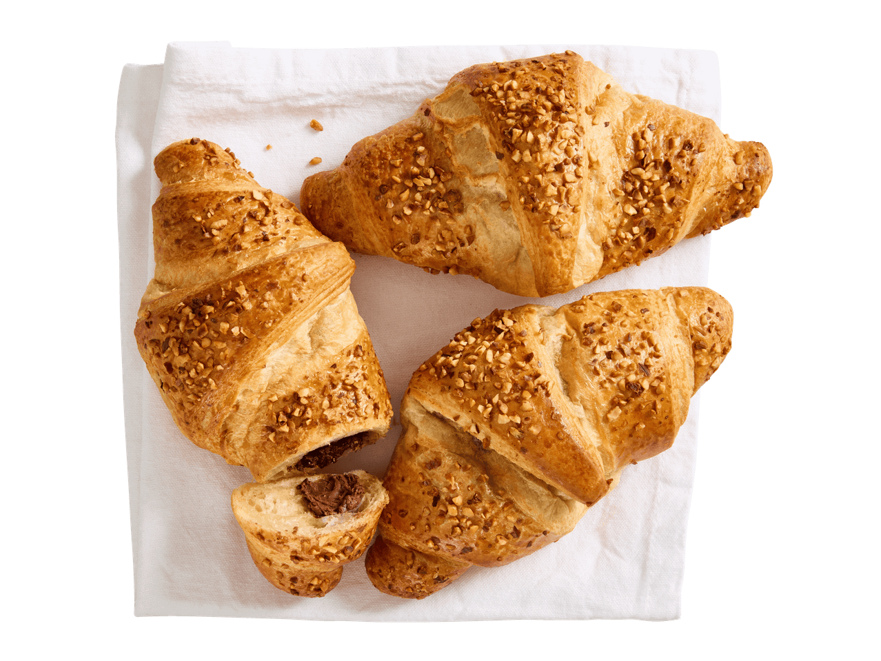 Kolme hasselpähkinä-suklaacroissanttia valkoisella liinalla, yksi leikattu kahtia.