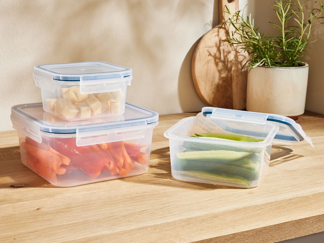 Stackable, clear plastic food storage containers on a kitchen counter.