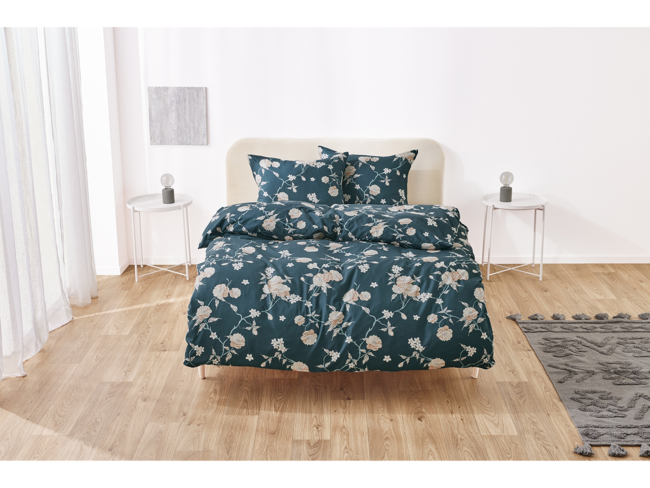 Set de lenjerie de pat floral turcoaz cu perne asortate pe un pat într-o cameră luminoasă.