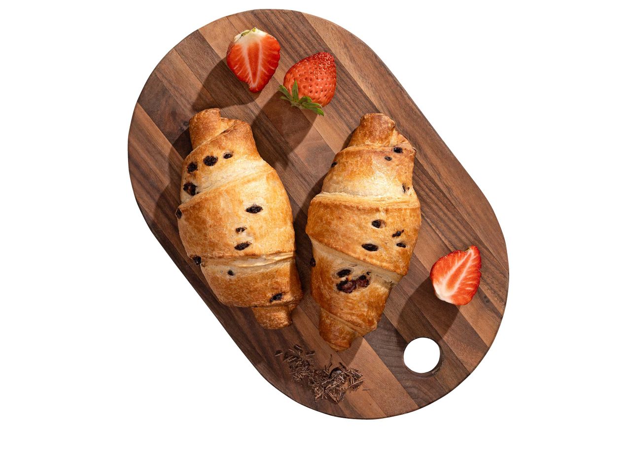 Két csokoládés croissant és eper egy fa vágódeszkán.