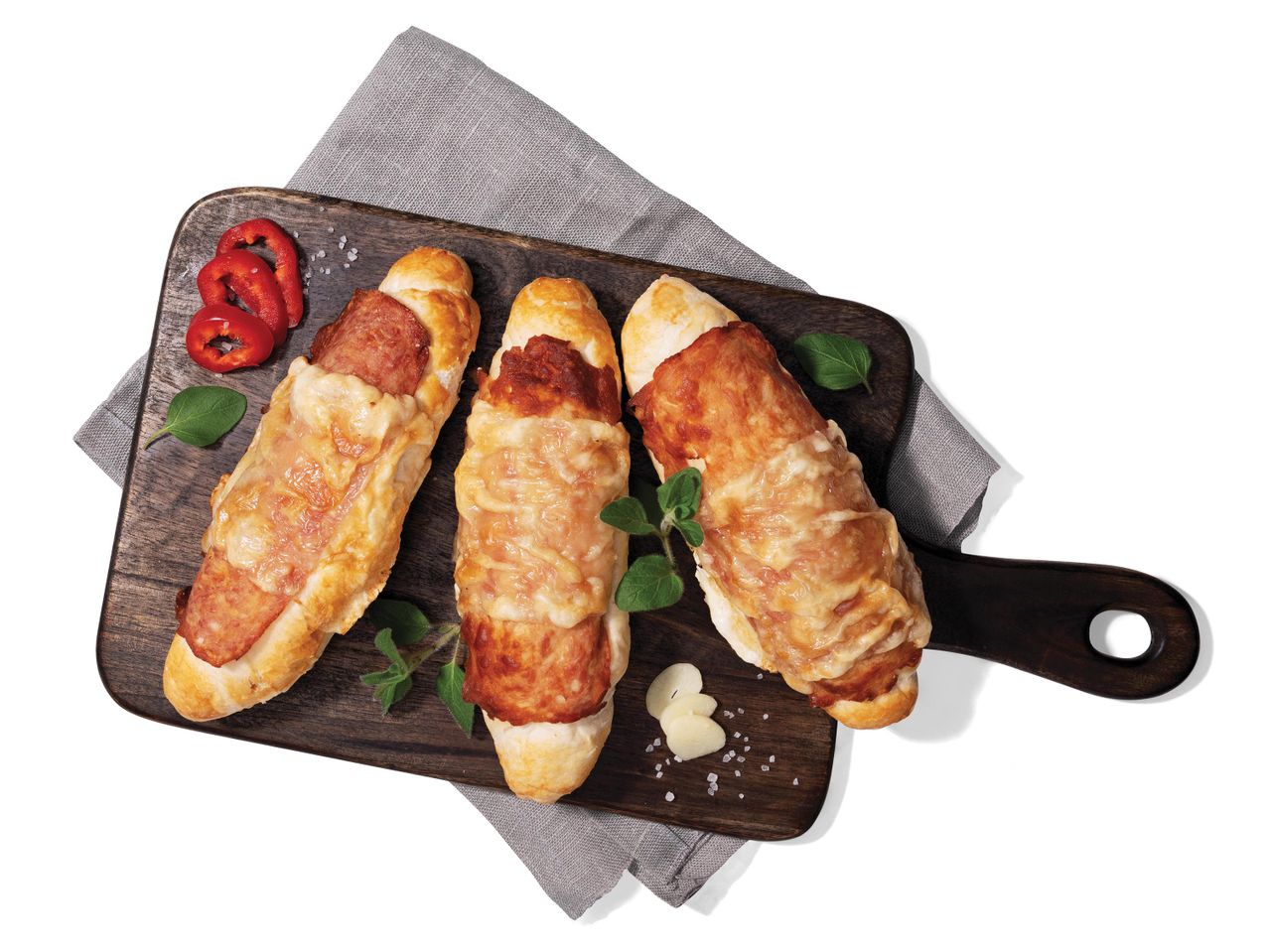 Három sonkás-sajtos croissant fa deszkán.