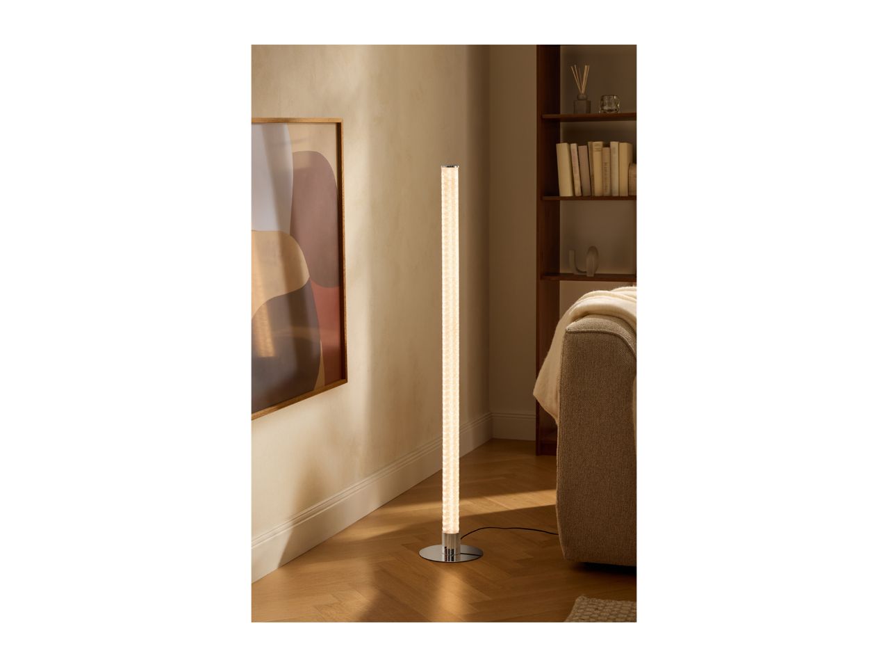 Tall floor lamp illuminating a cozy living room with a sofa and bookshelf.