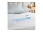 Spilled blue liquid on a white waterproof mattress protector with pillows and a bedside table.