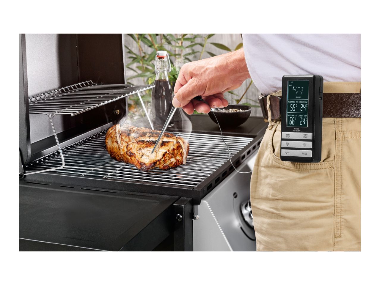 Man grilling meat with a digital thermometer clipped to his belt.