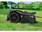 Robotic lawnmower on a green lawn with a house and trees in the background.
