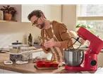 Man baking with a red SilverCrest stand mixer and silicone muffin tray.