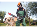Muškarac s motornom pilom Parkside reže drva na Stihl stalku.