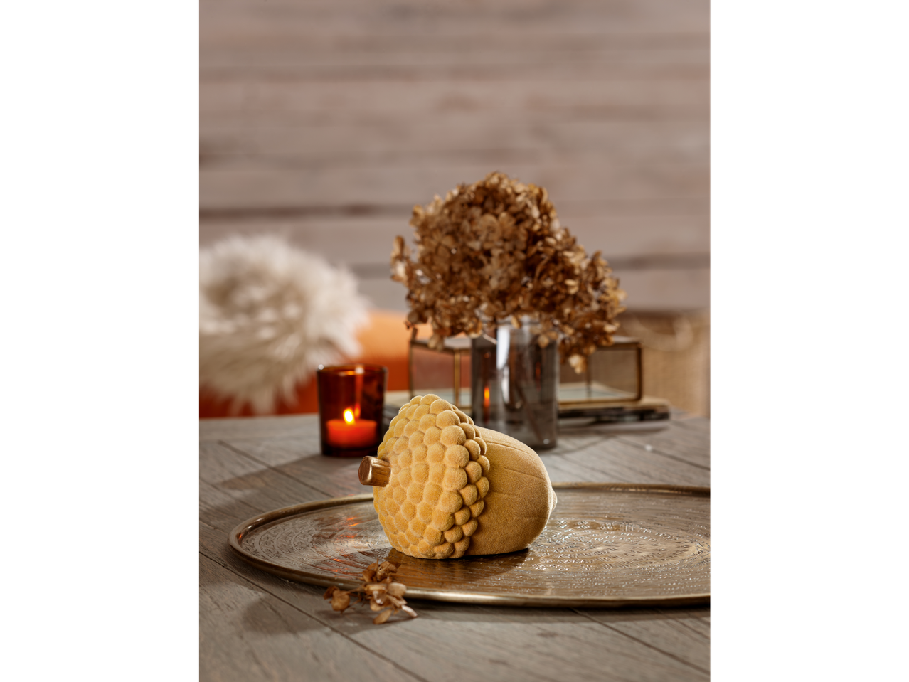 Autumnal acorn decoration on a tray with candles and dried flowers.