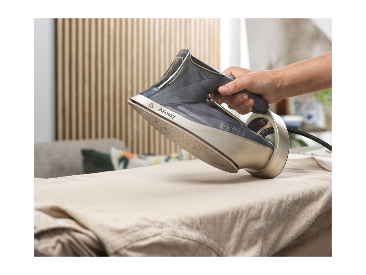 A person ironing a light-colored garment with a steam iron on an ironing board.