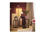 A living room with a floor lamp, a table lamp, and a vase of flowers on black side tables.