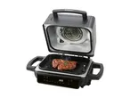 A black electric indoor grill with a steak cooking inside.