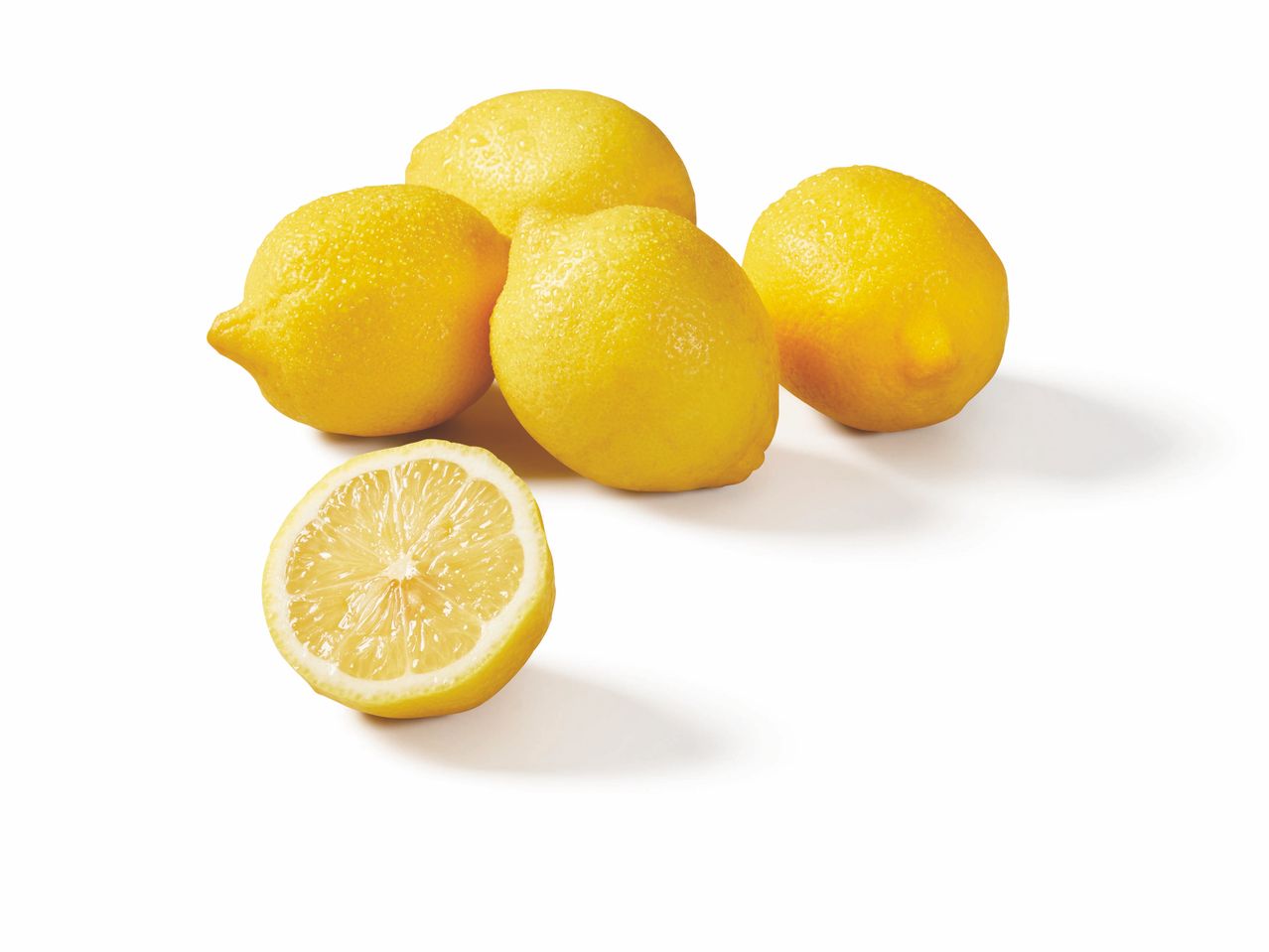 Quatre citrons entiers et une moitié de citron sur fond blanc.