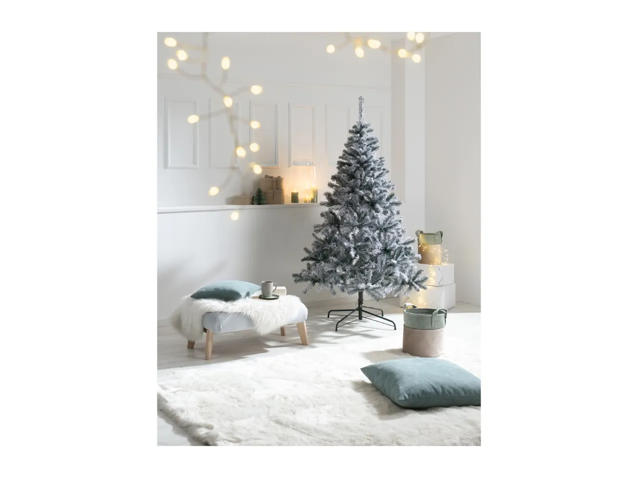 Flocked Christmas tree in a white room with a faux fur rug and festive decorations.