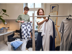 Two people hanging clothes on a rack with W5 Coat Hangers.