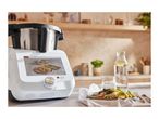 A Monsieur Cuisine Smart food processor displaying a recipe, with a prepared meal beside it.