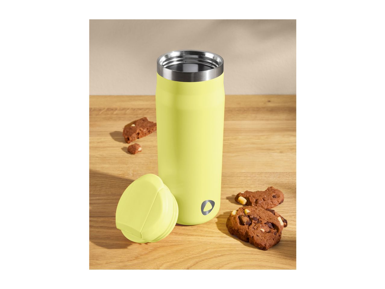 Lime green travel mug with lid and chocolate chip cookies on a wooden surface.