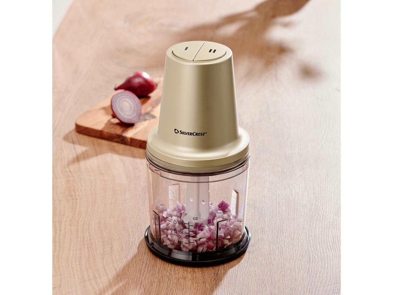 SilverCrest elektriline hakkija hakitud punase sibulaga puidust laual.