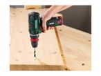 Cordless drill driving a screw into a wooden plank on a workbench.