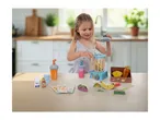 A young girl playing with a wooden toy blender set, including fruit, cups, and recipe cards.
