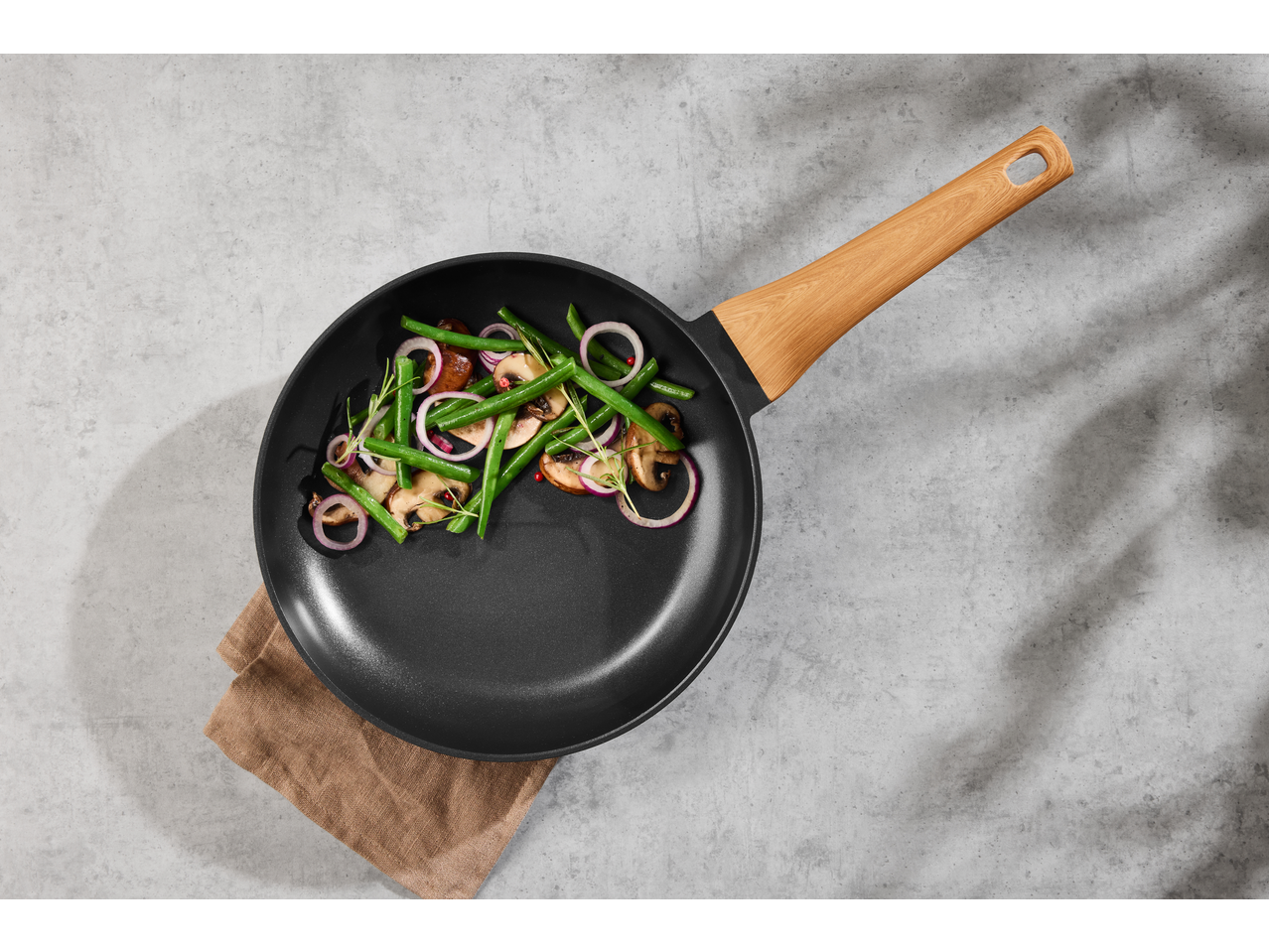 Frigideira de alumínio SILVERCREST com vegetais salteados sobre fundo cinzento.