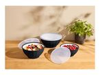 Black bowls with lids, one with salad, one with berries, on a wooden table.