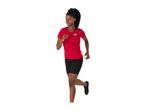 Woman running in a red short-sleeved sports top and black cycling shorts.
