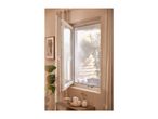 Open window with a mosquito net, light curtains, and a wooden side table with candles.