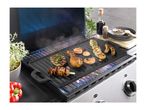 Grill with various meats and shrimp cooking, with spices and a red pepper nearby.
