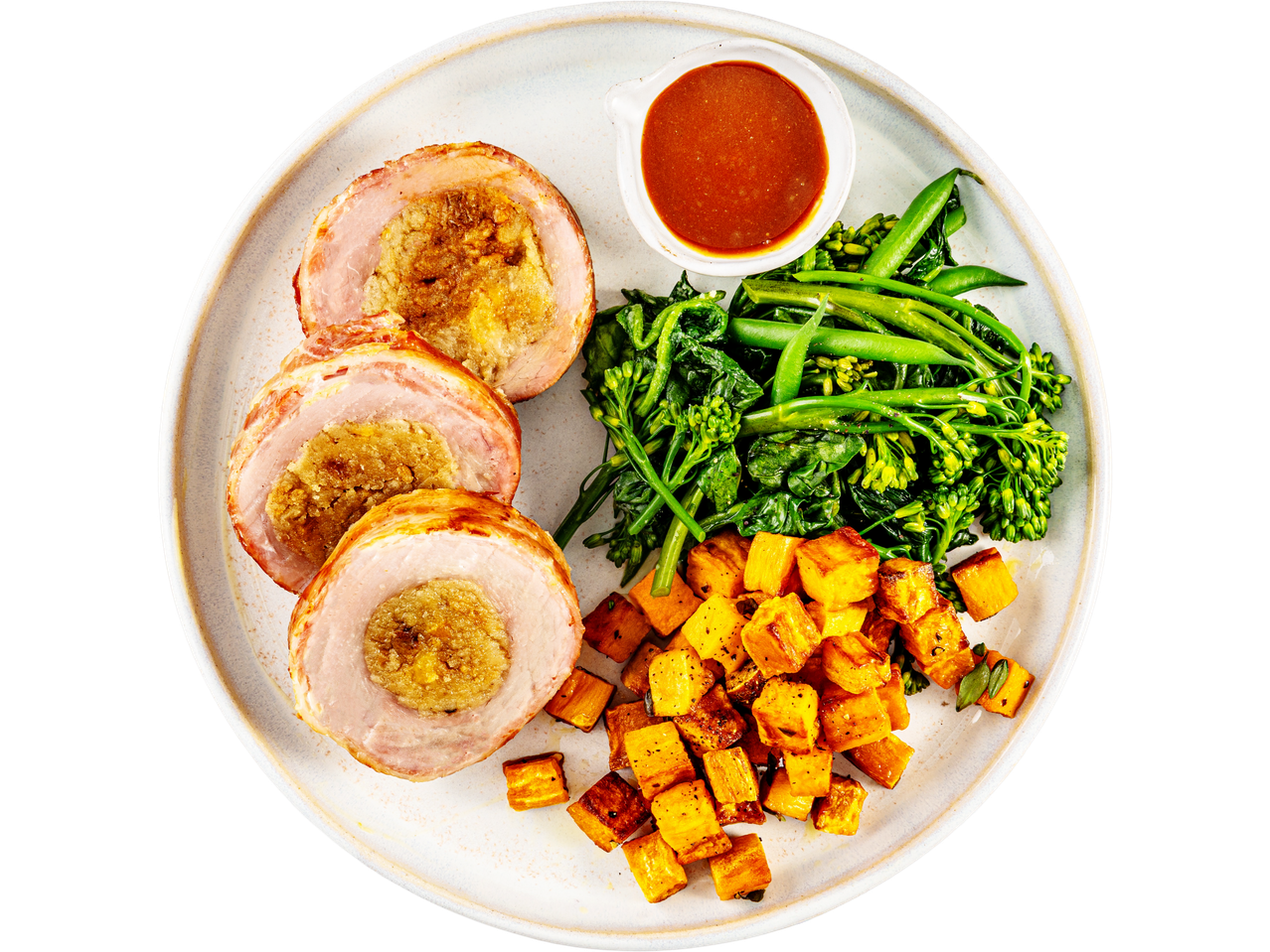 Pork roulade with stuffing, roasted sweet potatoes, broccolini, and a side of gravy.