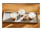Three glasses of latte macchiato and biscotti on a concrete tray.