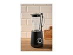 Black blender with a glass jug on a wooden countertop against a tiled wall.