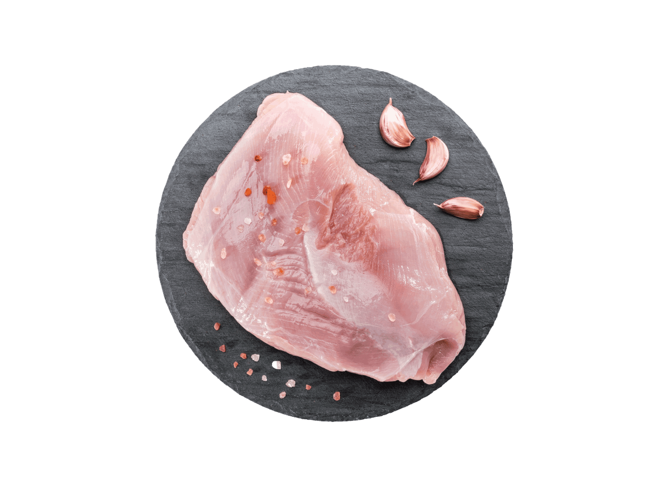 Žalia kalakutienos filė su druska ir česnaku ant juodos apvalios lentelės.