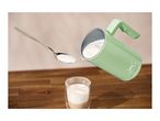 A SilverCrest milk frother pouring frothed milk into a glass with a spoon of milk floating nearby.