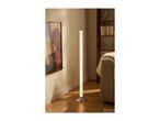 Tall floor lamp illuminating a cozy living room with a sofa and bookshelf.
