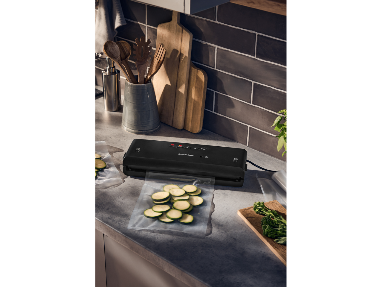 Máquina de vácuo Silvercrest® na bancada da cozinha com curgete em sacos de vácuo.