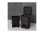 Two dark grey plastic bins, one with a lid and foot pedal, on a tiled floor.