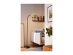 Modern black floor lamp illuminating a cozy living room with a sofa and decor.