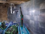 A Parkside work light illuminates a sink pipe and blue tiles.