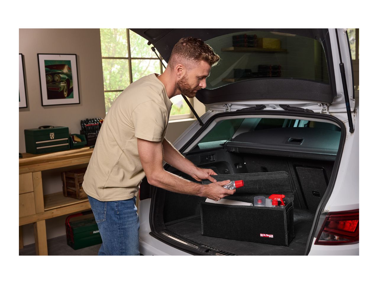 Man placing car cleaning products in a trunk organizer in a car trunk.