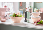 Pink and mint kitchenware: salad in a bowl, pepper and salt grinders, and other accessories.