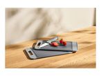 Two grey plastic cutting boards with a knife and cherry tomatoes on a wooden surface.