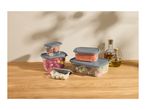 Clear food containers with grey lids, filled with fresh food, on a wooden table.