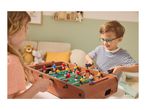 Two children playing foosball, a girl on the left and a boy in glasses on the right.