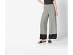 Pantaloni palazzo a stampa geometrica con fondo nero e sandali piatti.