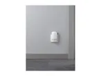 A white night light with a motion sensor plugged into a wall outlet.