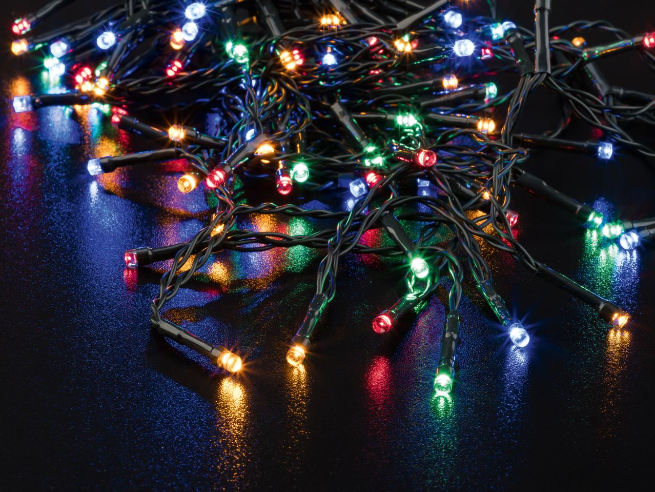 Close-up of tangled colorful LED string lights on a dark, reflective surface.