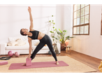Femeie practicând yoga cu bloc și minge de pilates acasă.