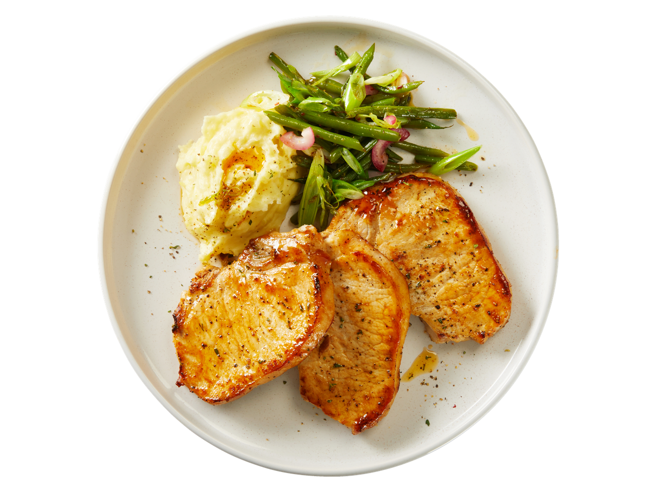 Three golden-brown pork chops with mashed potatoes and green beans on a white plate.