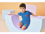 Boy in blue Spider-Man jersey shorts and matching t-shirt, sitting in a curved prop.